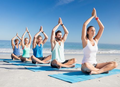 people-doing-yoga-on-the-beach-e1681803021989.jpg